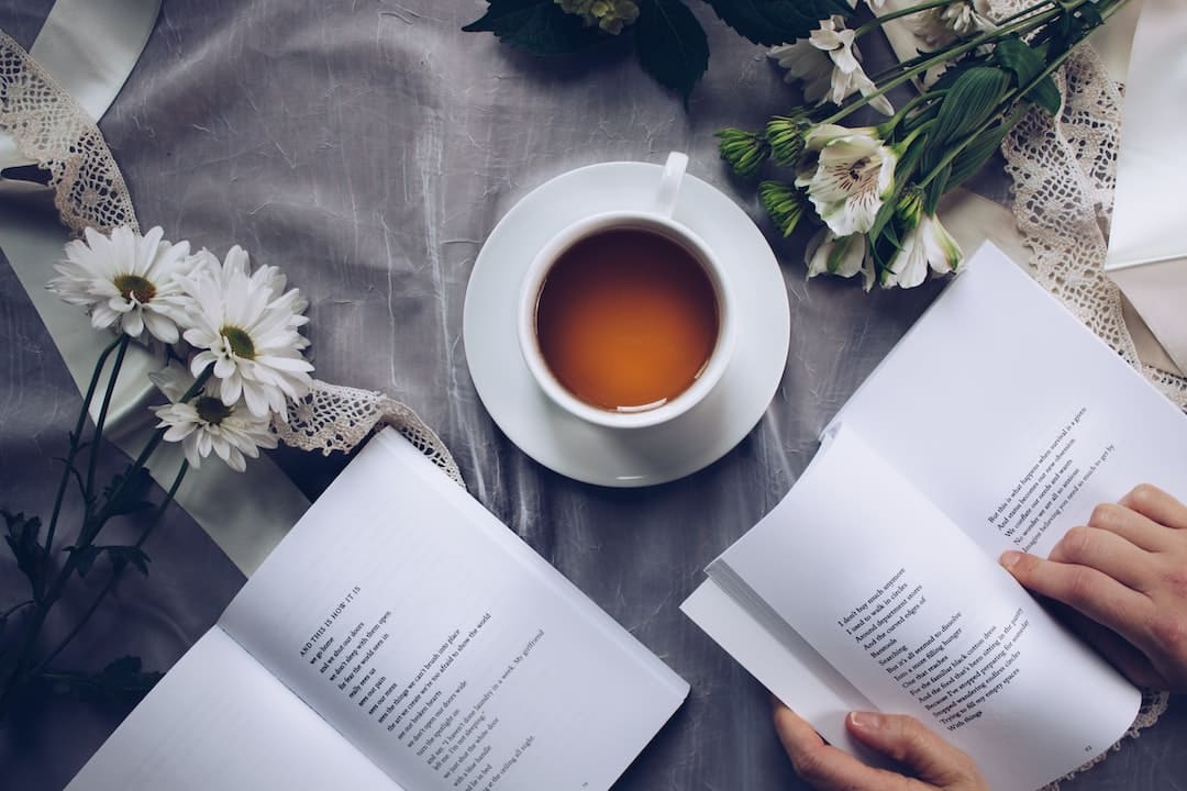 somebody reading books with tea and flowers around